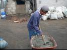 Local young man helping by mixing mortar for his familiy's stove