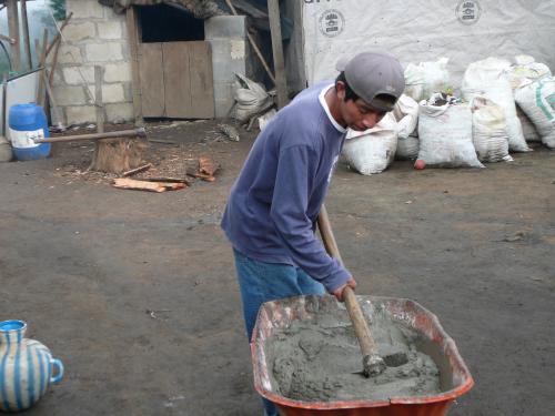 Local young man helping by mixing mortar for his familiy's stove